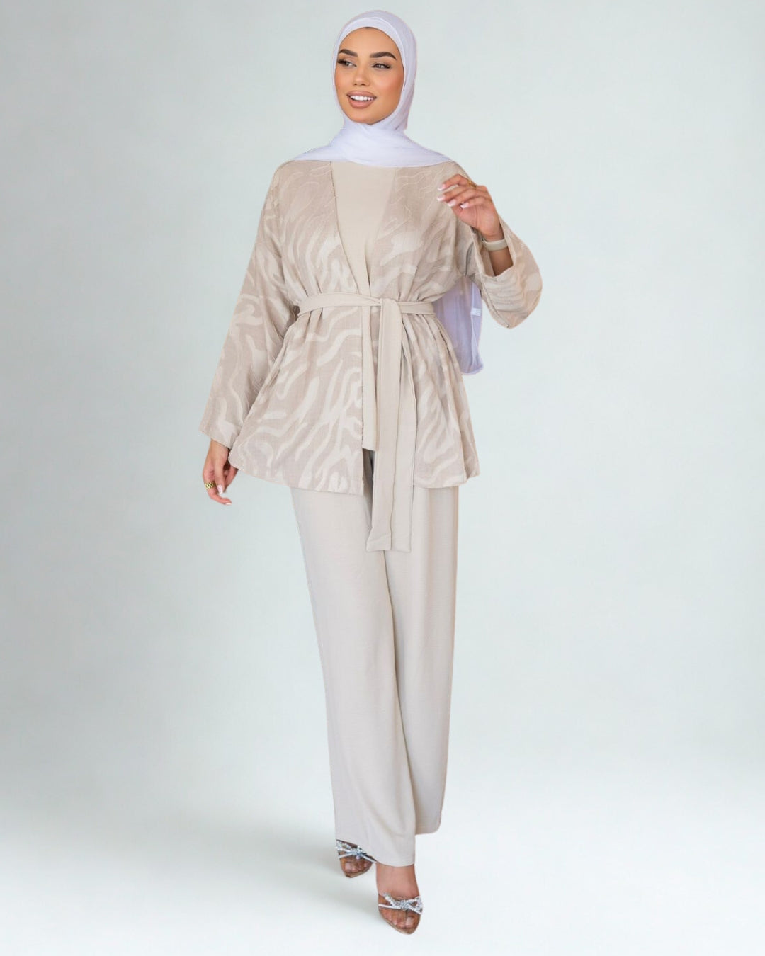 Woman wearing a beige outfit with a matching hijab on a white background