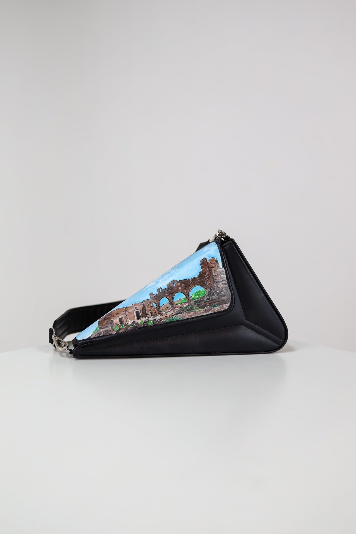 Triangular pouch with a scenic design on a light gray background