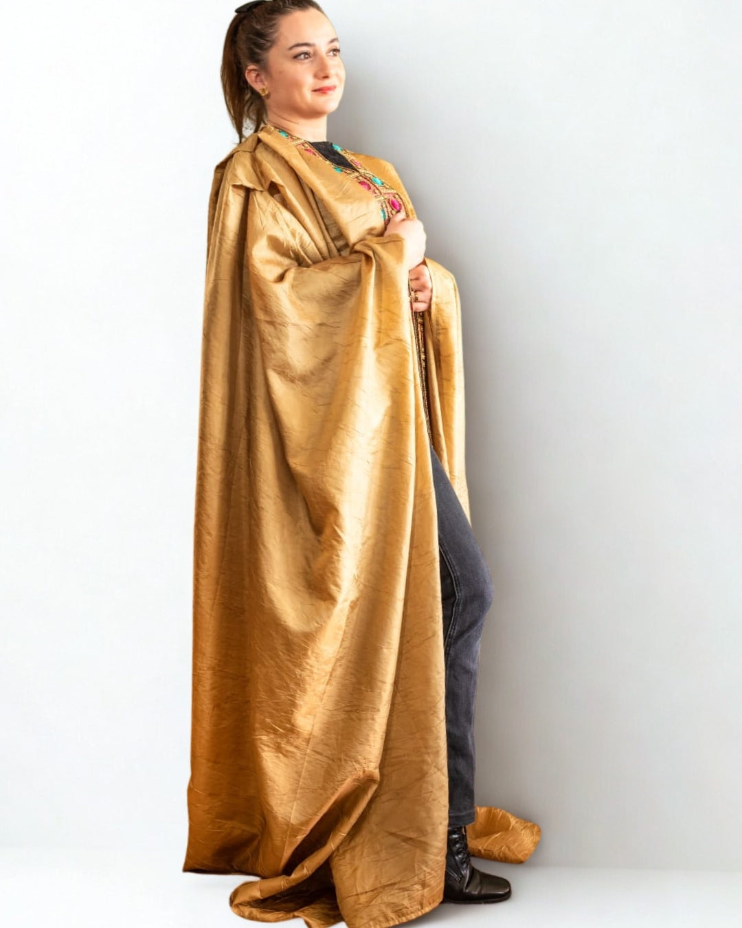 Person wearing a gold cape against a white background