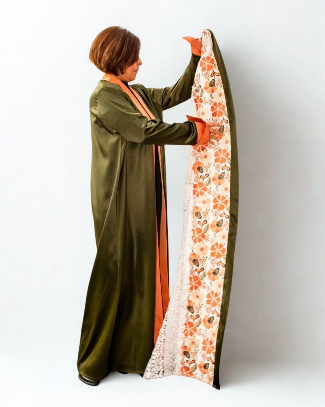 Person holding a long, patterned fabric with floral design against a plain background