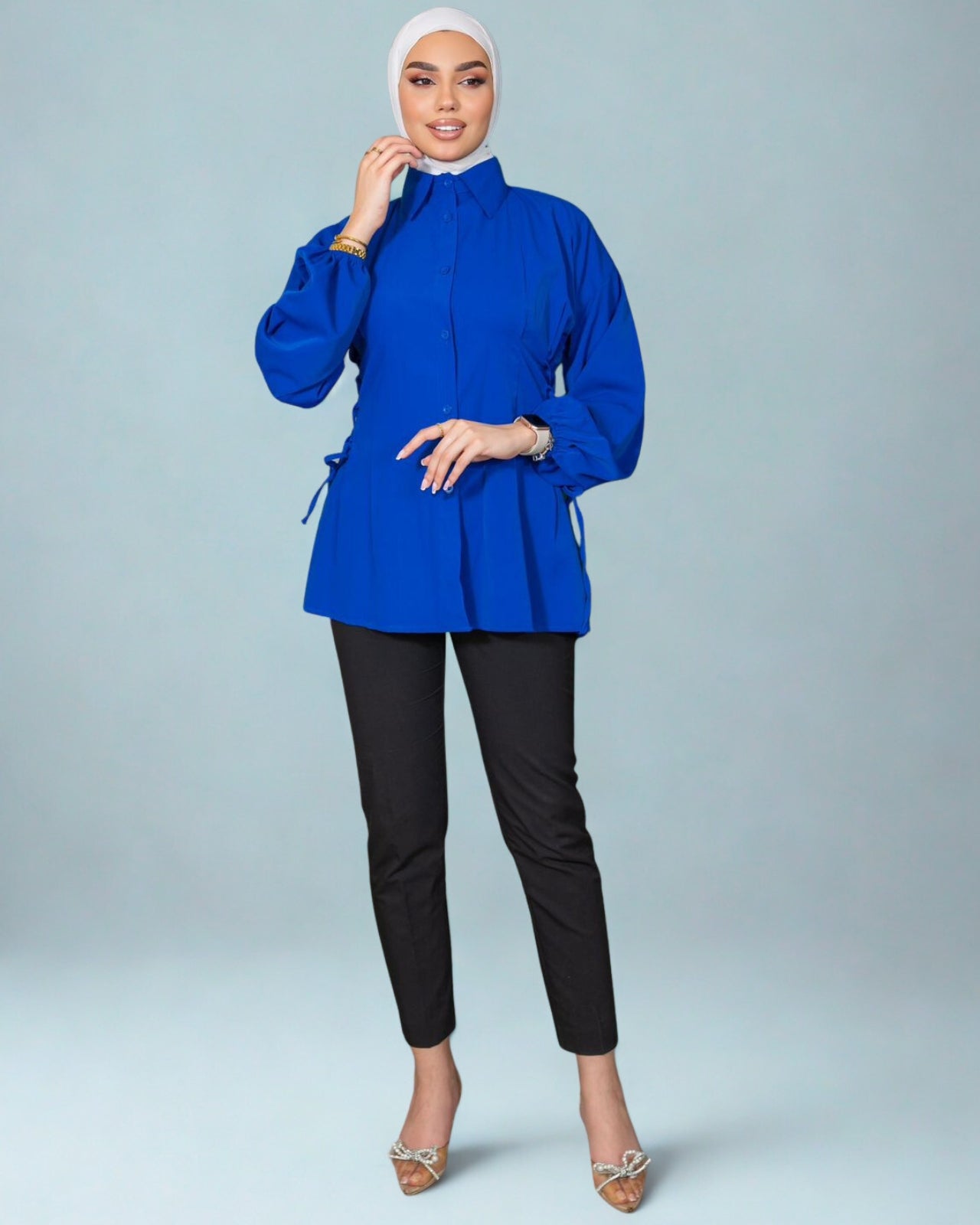 Woman wearing a blue top and black pants on a gray background
