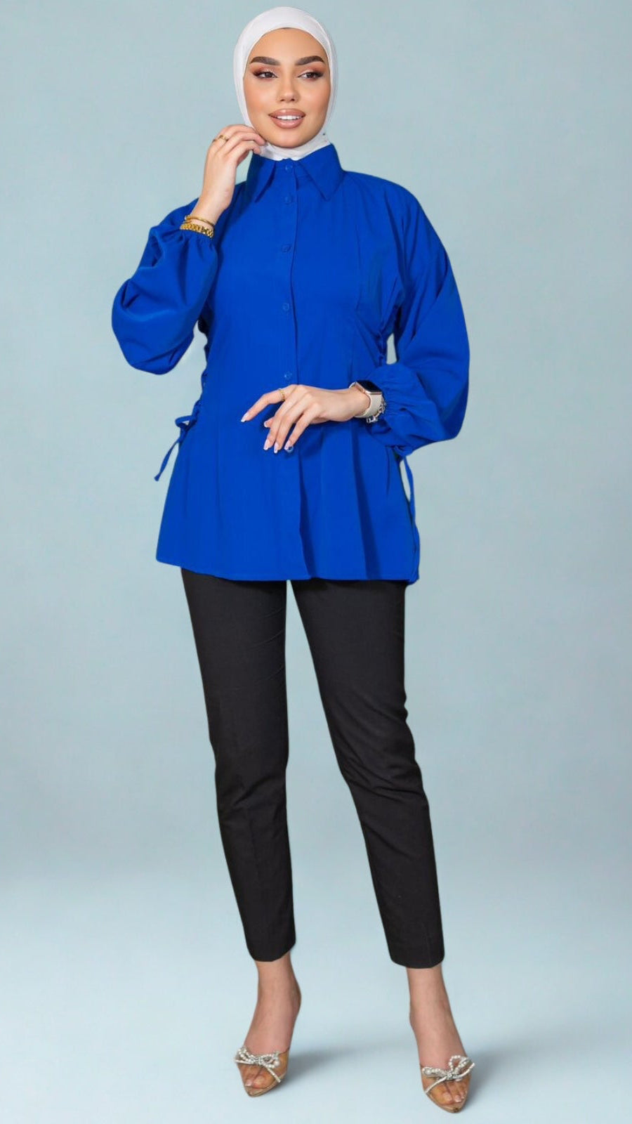 Woman wearing a blue top and black pants on a gray background
