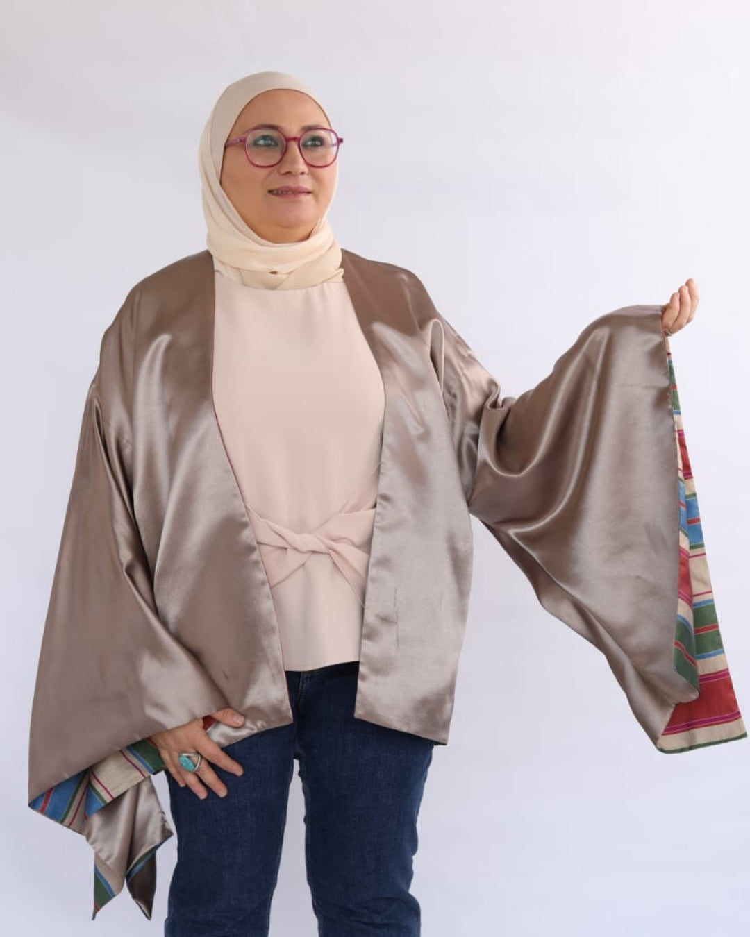 Woman wearing a beige hijab and brown satin shawl on a white background