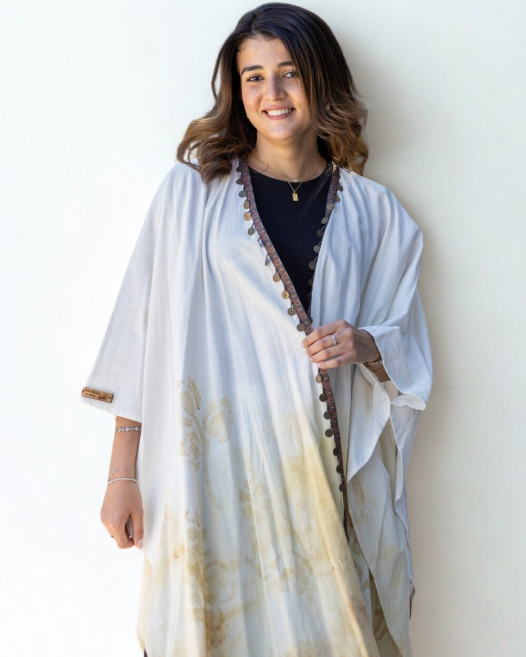 Woman wearing a white and beige patterned shawl against a plain background