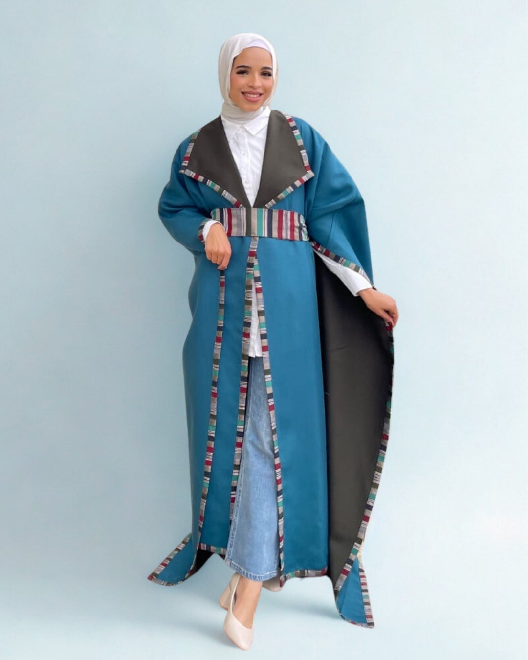 Woman wearing a long, patterned blue and gray coat against a light blue background