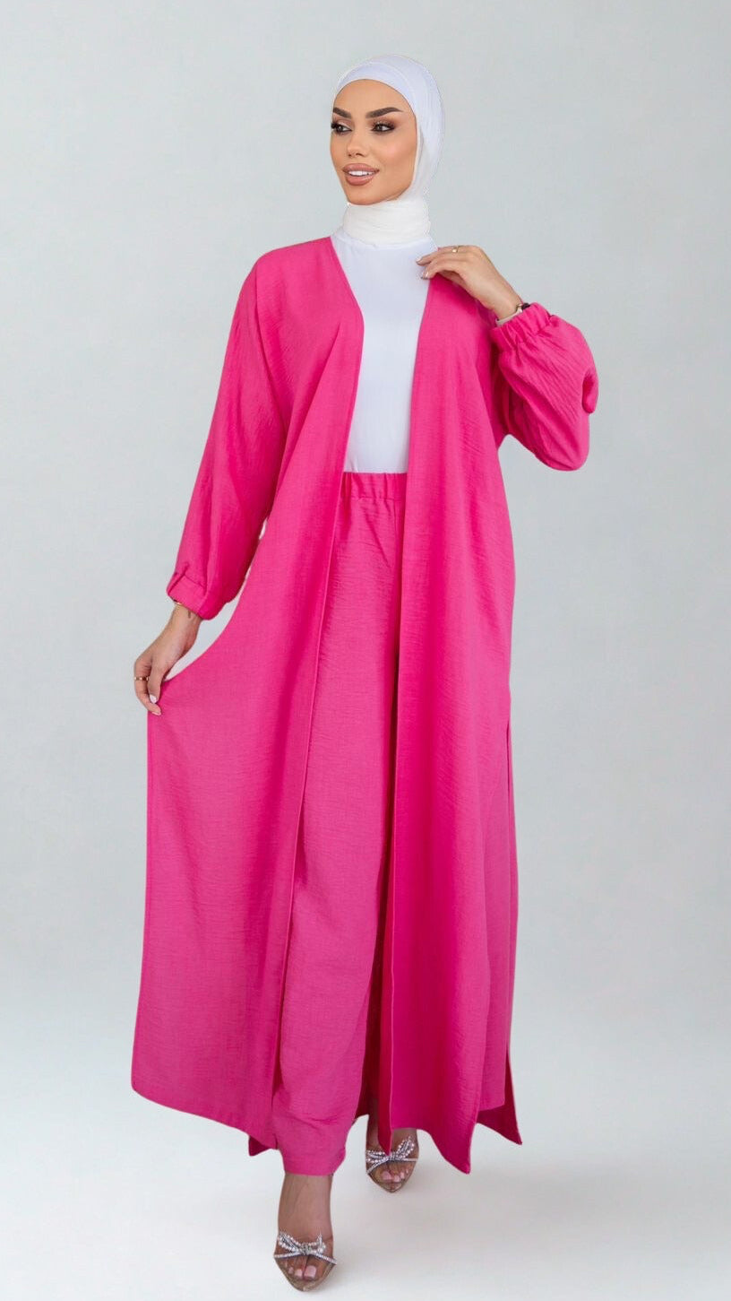 Woman wearing a bright pink abaya with a white hijab on a white background