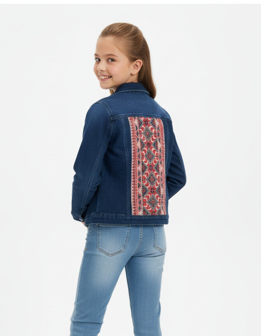 Girl wearing a blue denim jacket with a colorful embroidered back panel on a white background