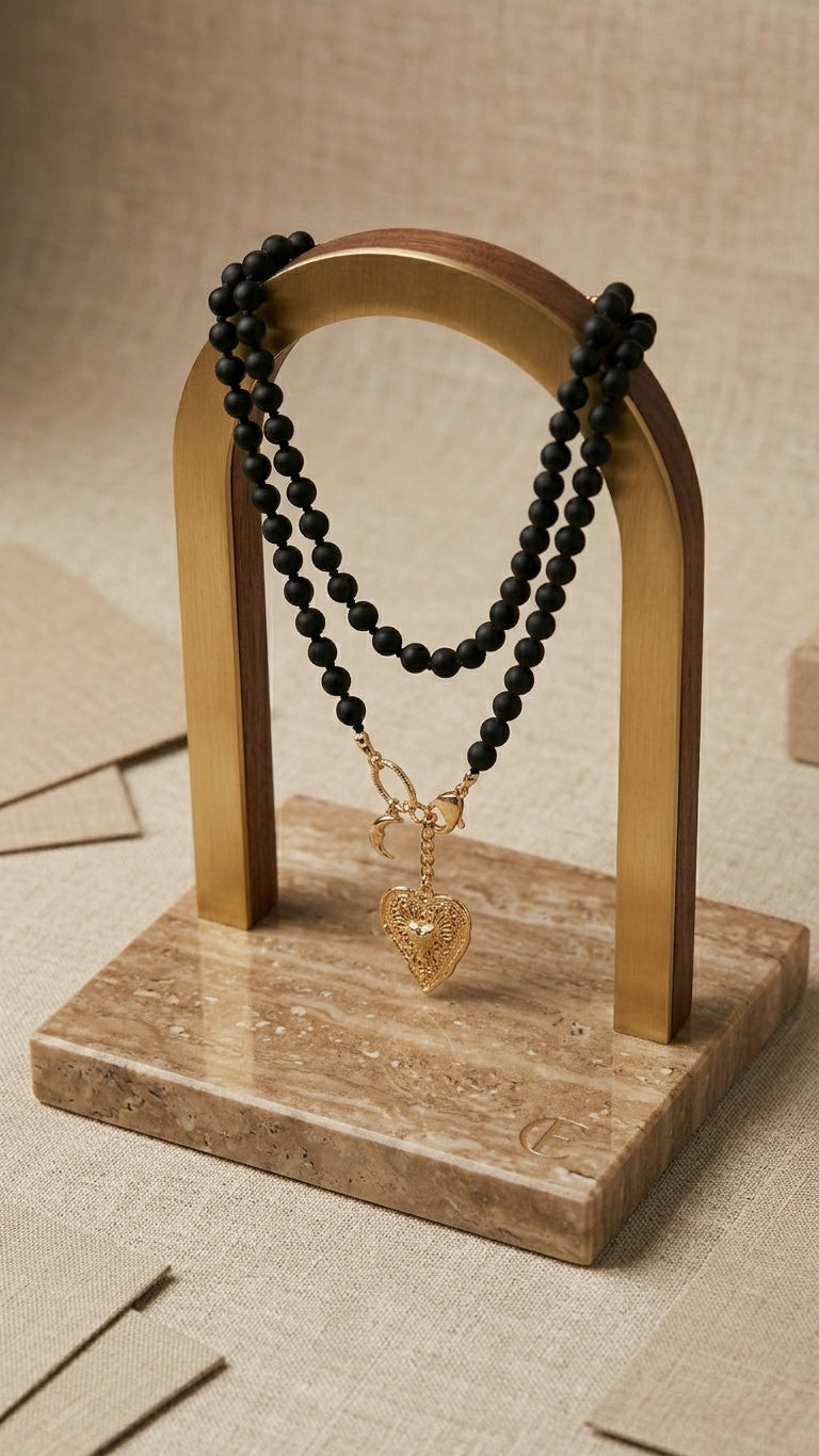 Black beaded necklace with a heart pendant on a wooden stand against a beige background