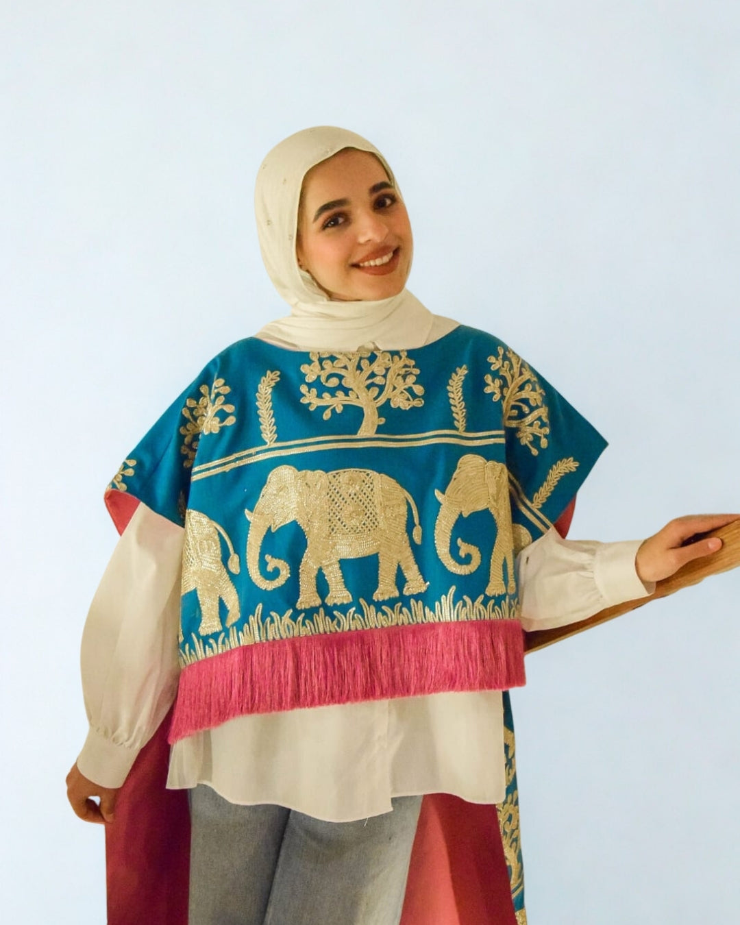 Woman wearing a colorful traditional outfit with elephant patterns on a light blue background