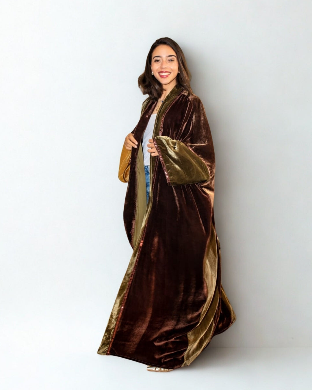 Woman wearing a long brown and gold robe against a white background