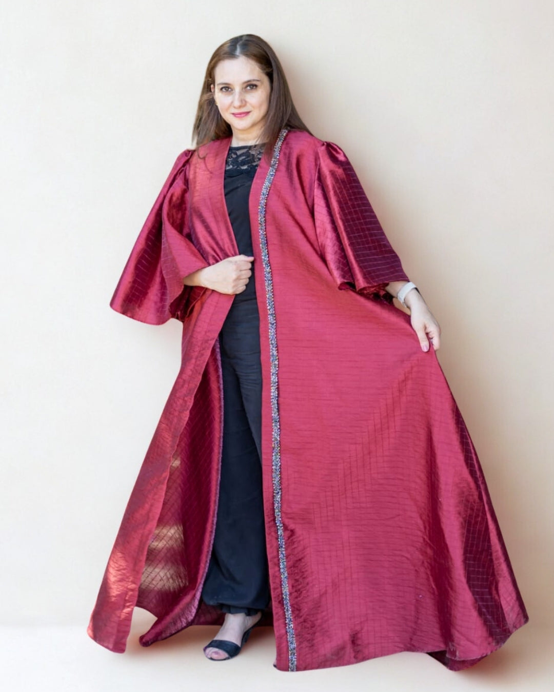 Woman wearing a long burgundy coat with a white background