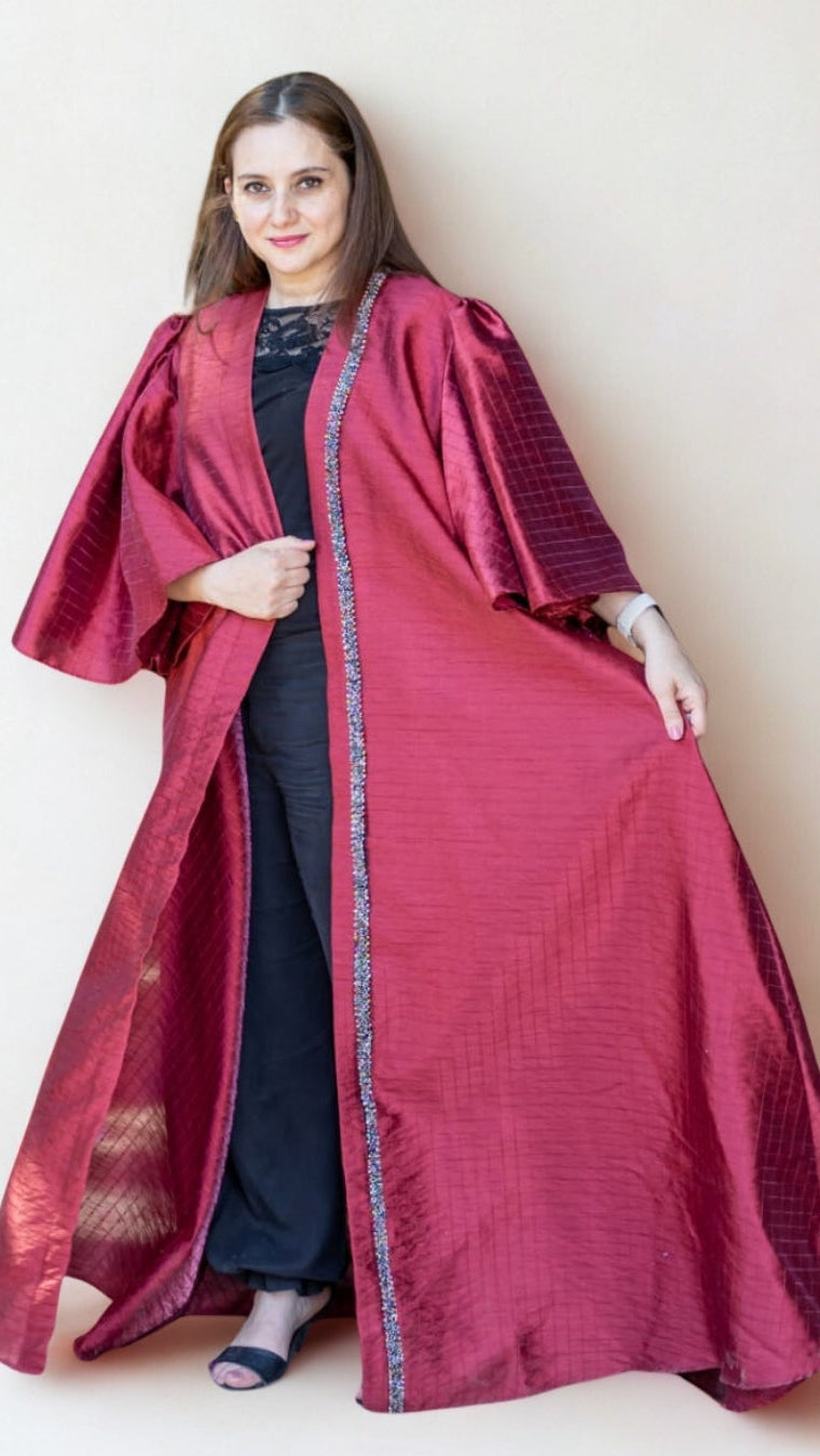 Woman wearing a long burgundy coat with a white background