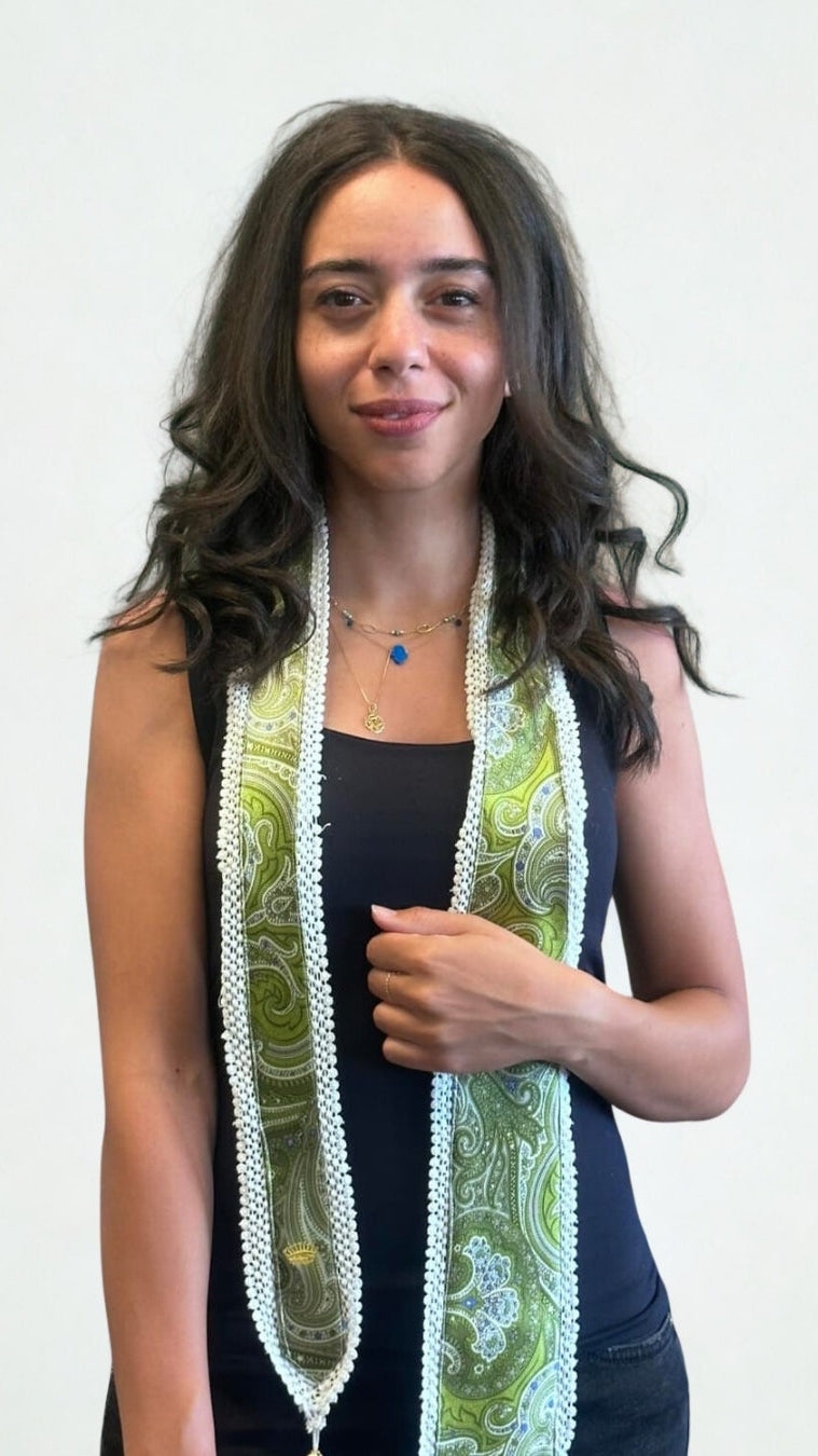 Woman wearing a long, patterned scarf against a plain background