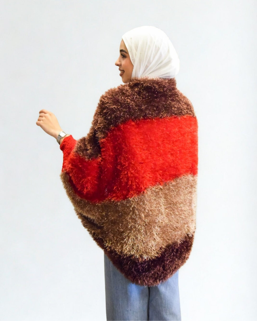 Person wearing a red and brown fuzzy poncho on a white background