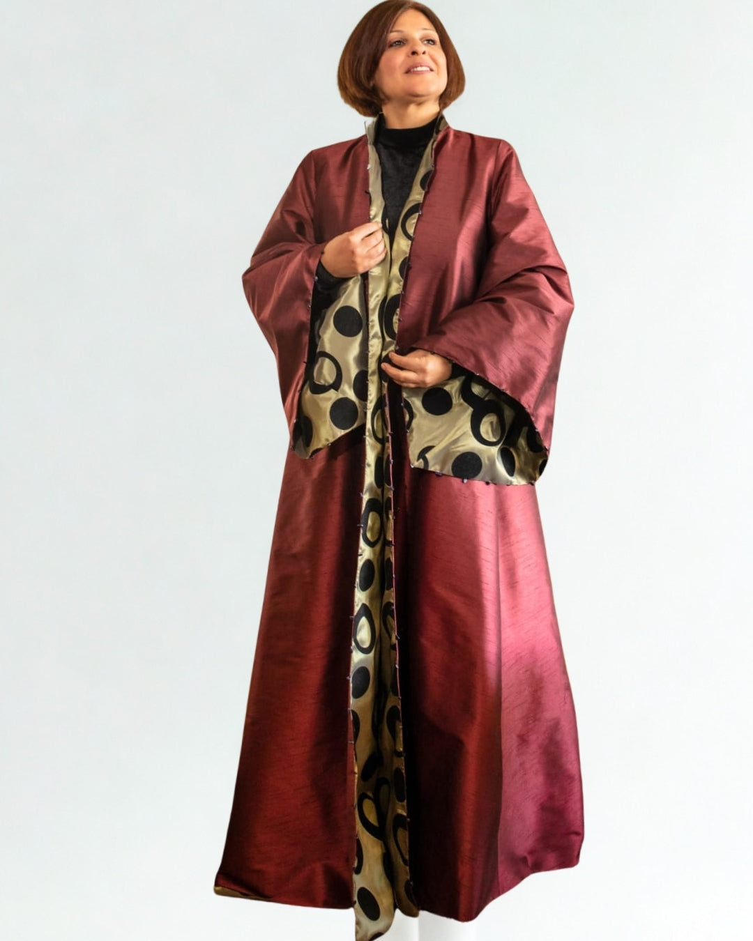 Woman wearing a long burgundy coat with a patterned scarf on a white background