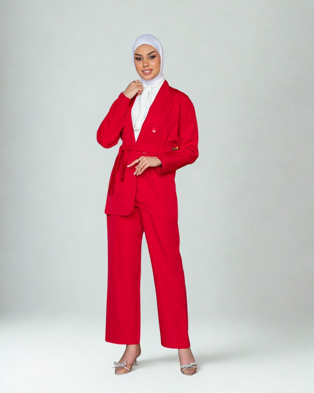 Person wearing a red suit with a white hijab on a light gray background