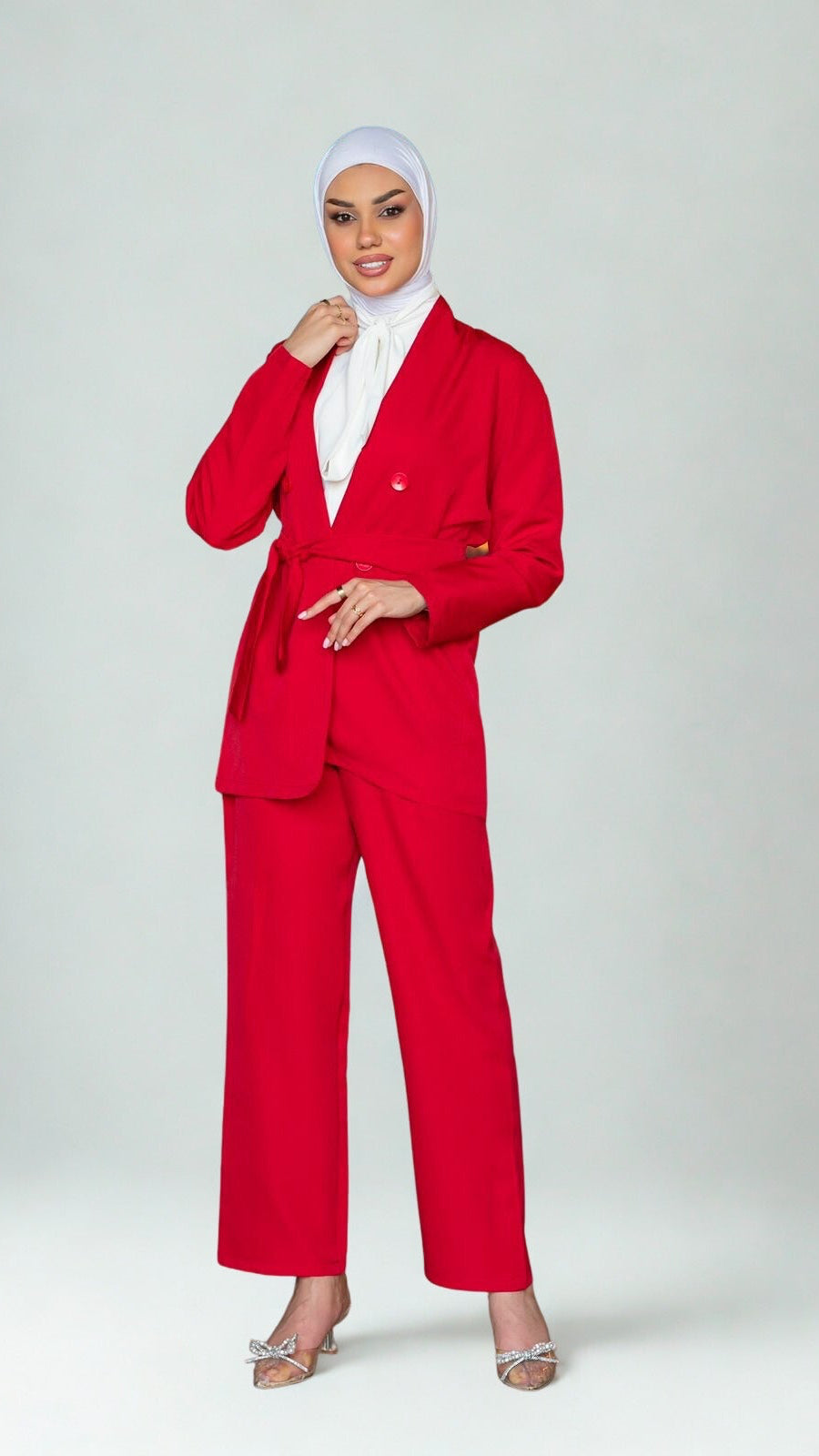 Person wearing a red suit with a white hijab on a light gray background