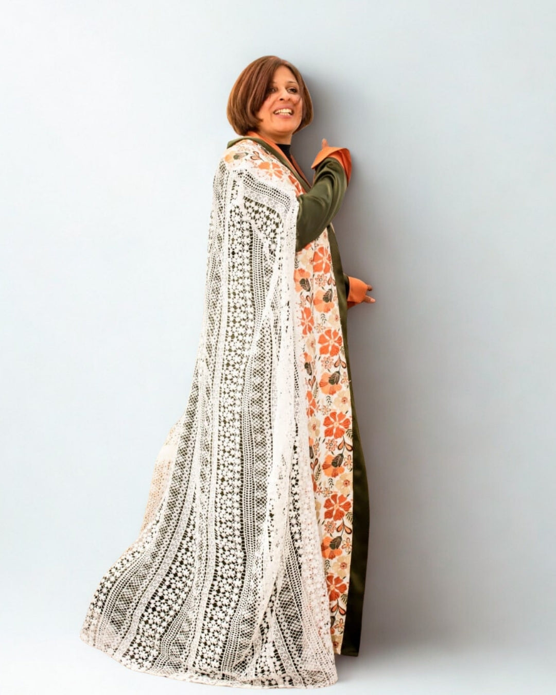 Woman wearing a long, patterned dress against a plain background