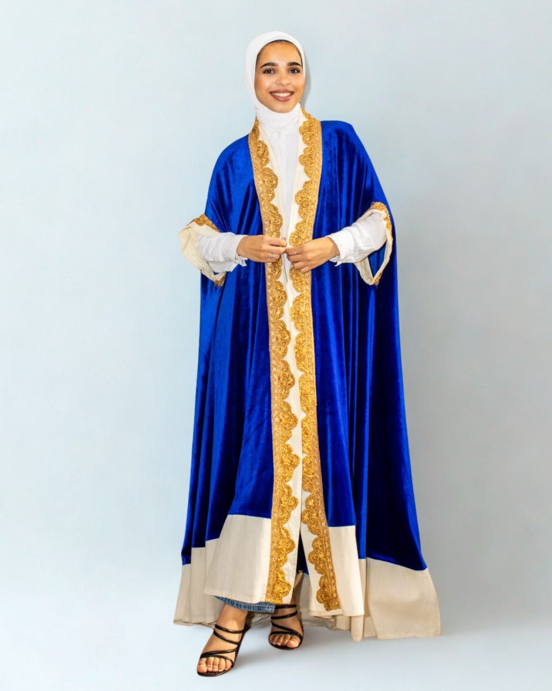 Woman wearing a blue and gold abaya on a light gray background