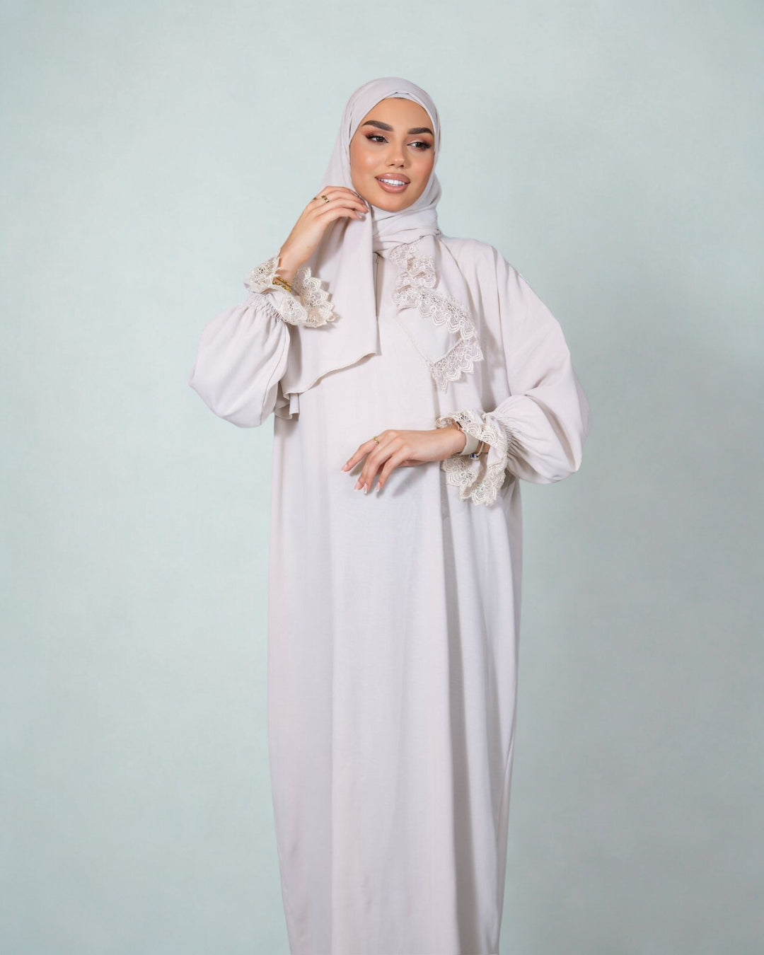 Woman wearing a white dress with floral details on a light gray background