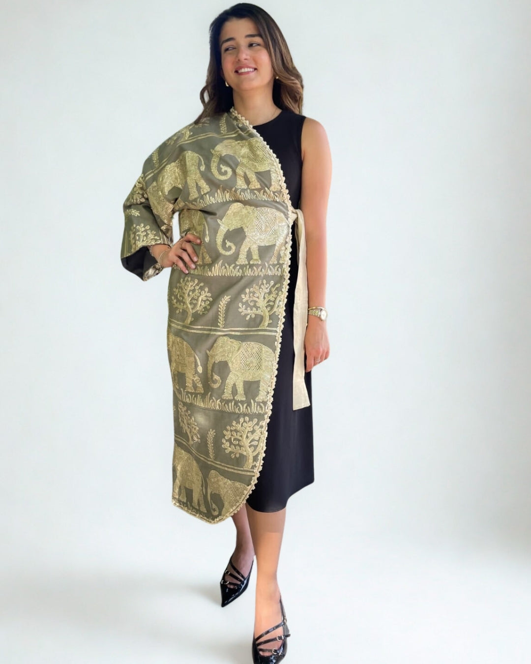 Woman wearing a patterned shawl over a black outfit on a white background