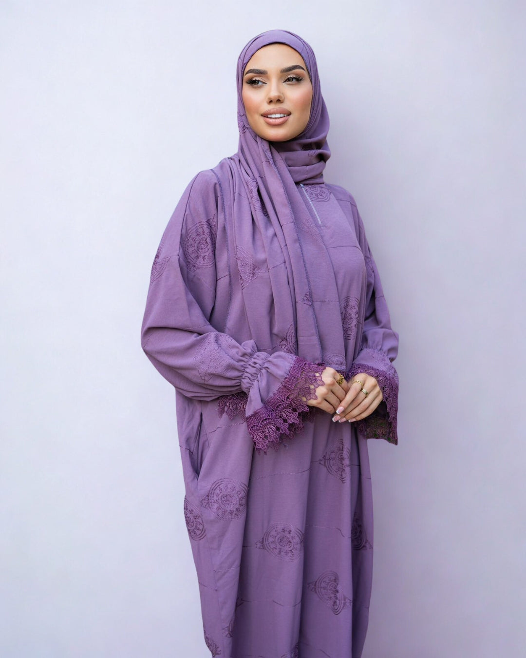 Woman wearing a purple abaya with lace details on a light gray background