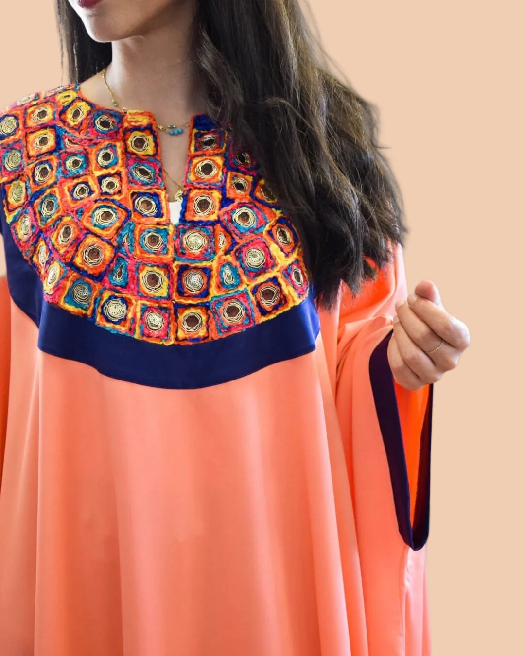 Woman wearing a colorful embroidered top with a plain background