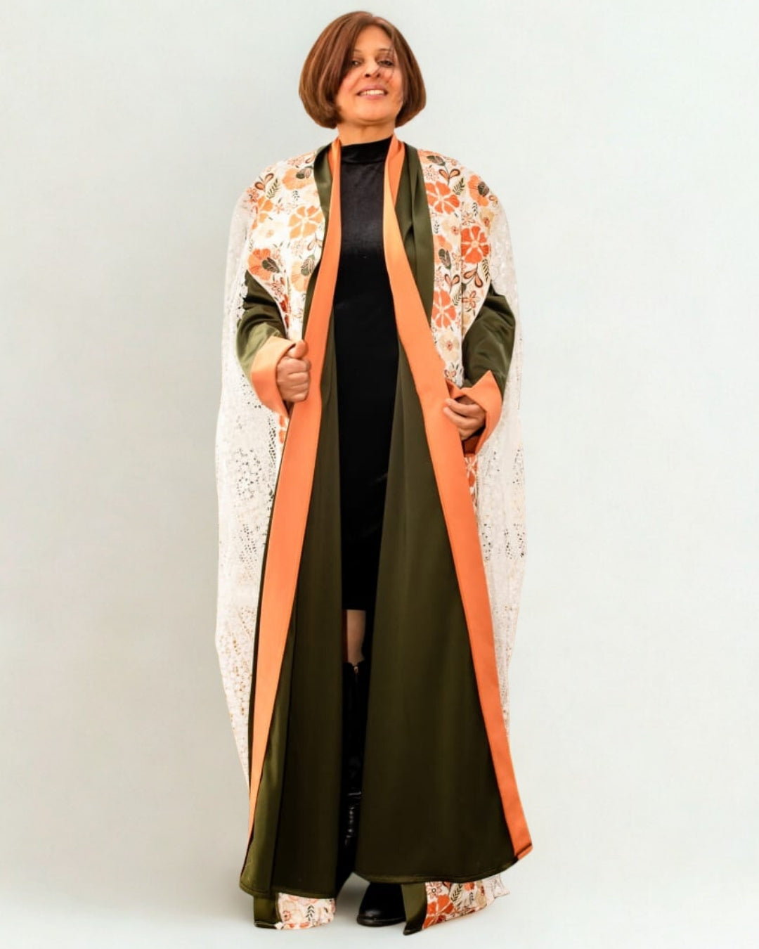 Woman wearing a long, patterned coat with a white background