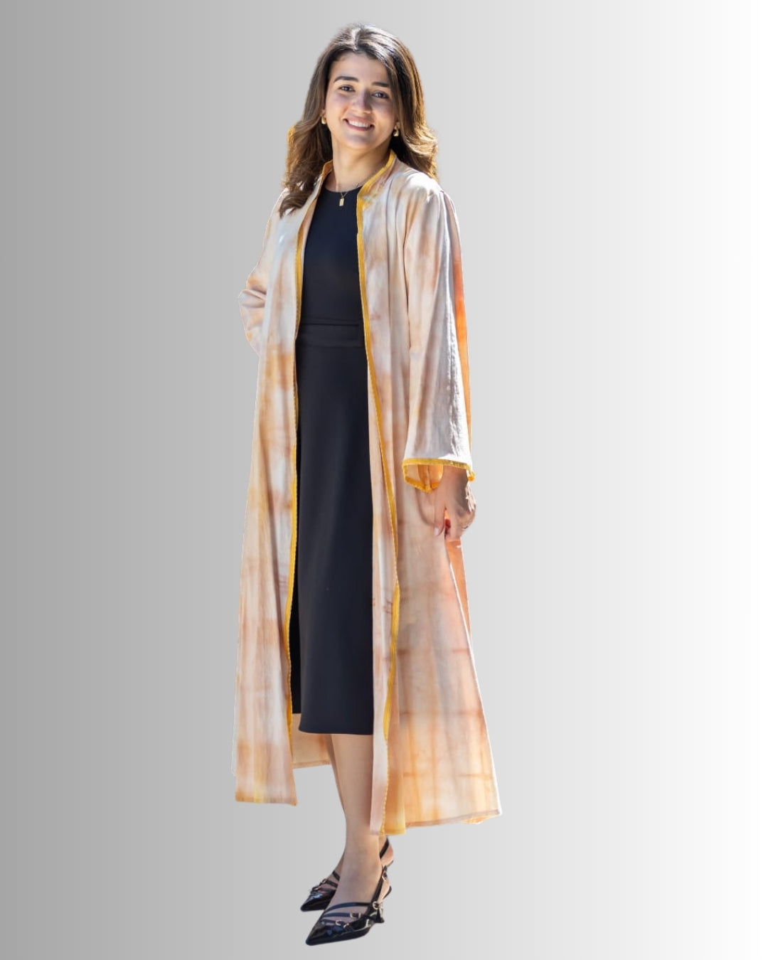 Woman wearing a long, sheer, multicolored jacket over a black outfit on a gray background