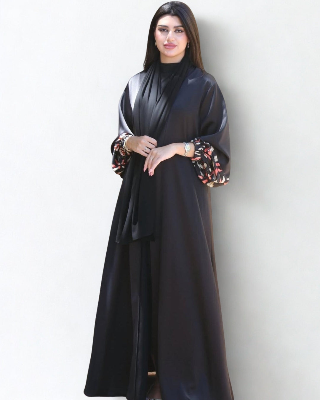 Woman wearing a black abaya with floral sleeves against a white background