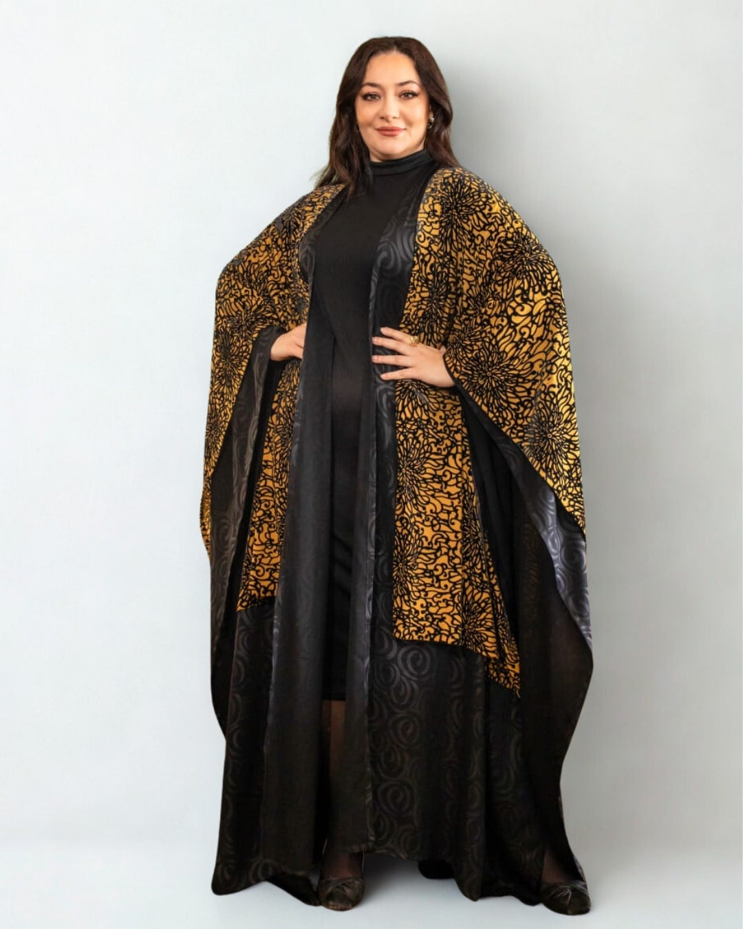 Woman wearing a black dress with a leopard print shawl on a white background