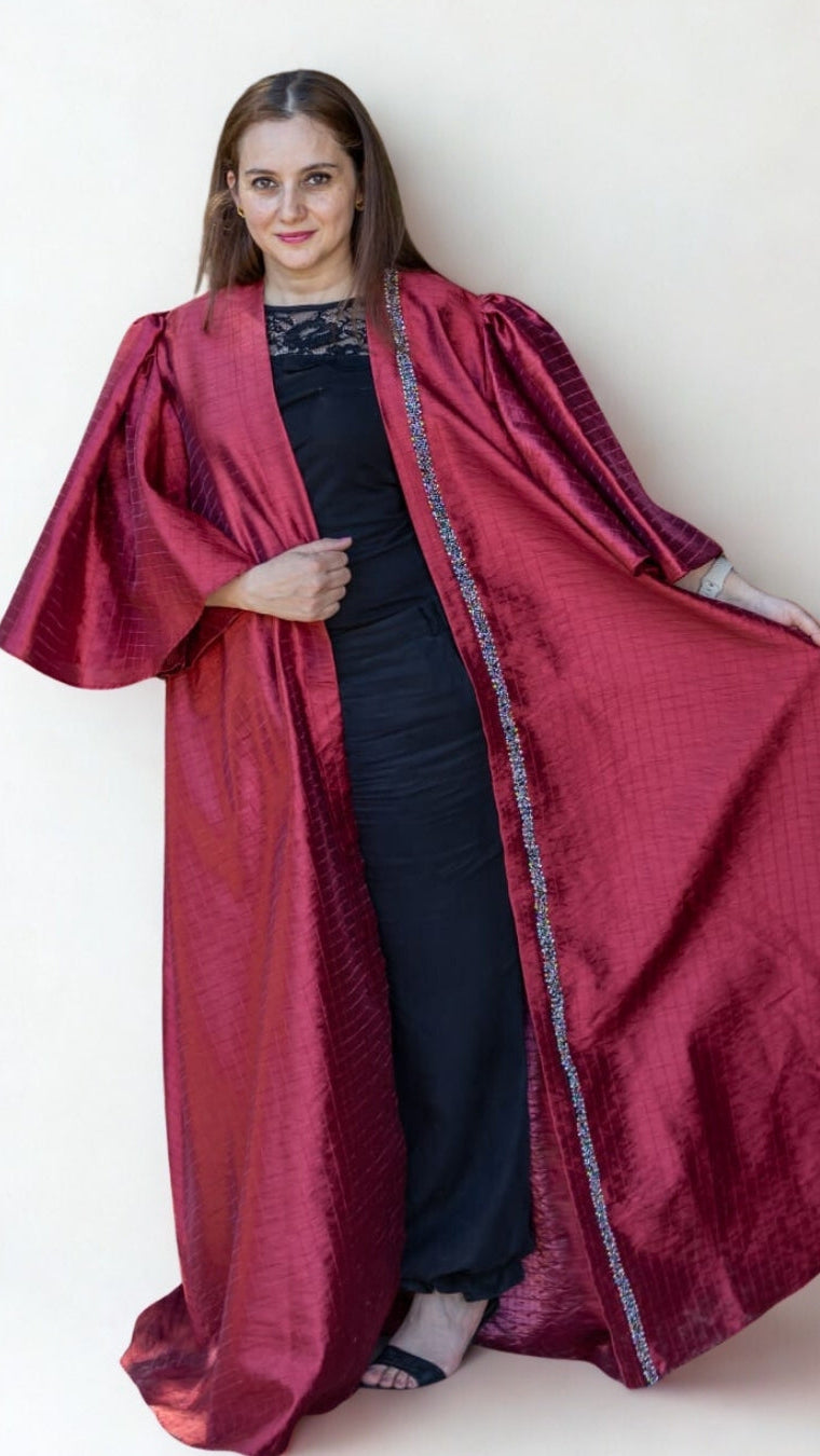 Woman wearing a long red robe over a black outfit against a white background