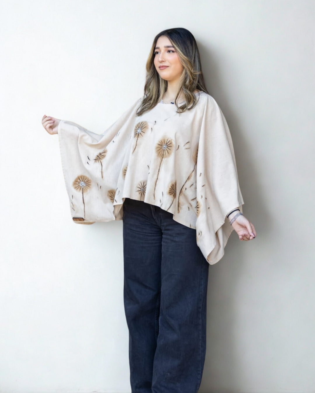 Woman wearing a beige floral poncho against a white background