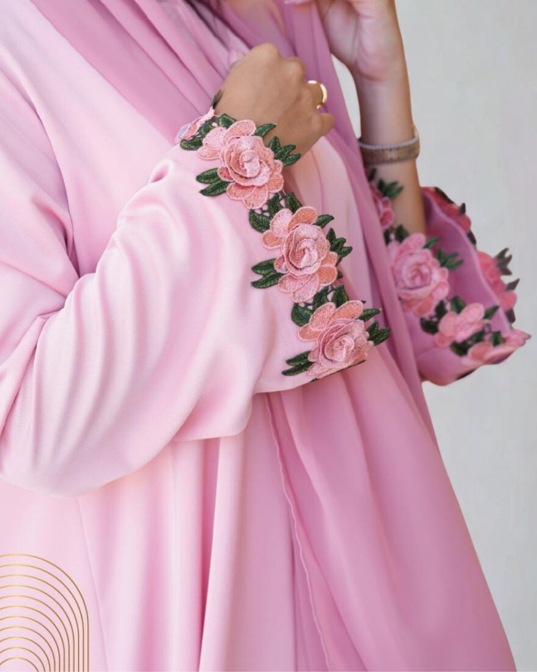 Pink outfit with floral embroidery on a plain background
