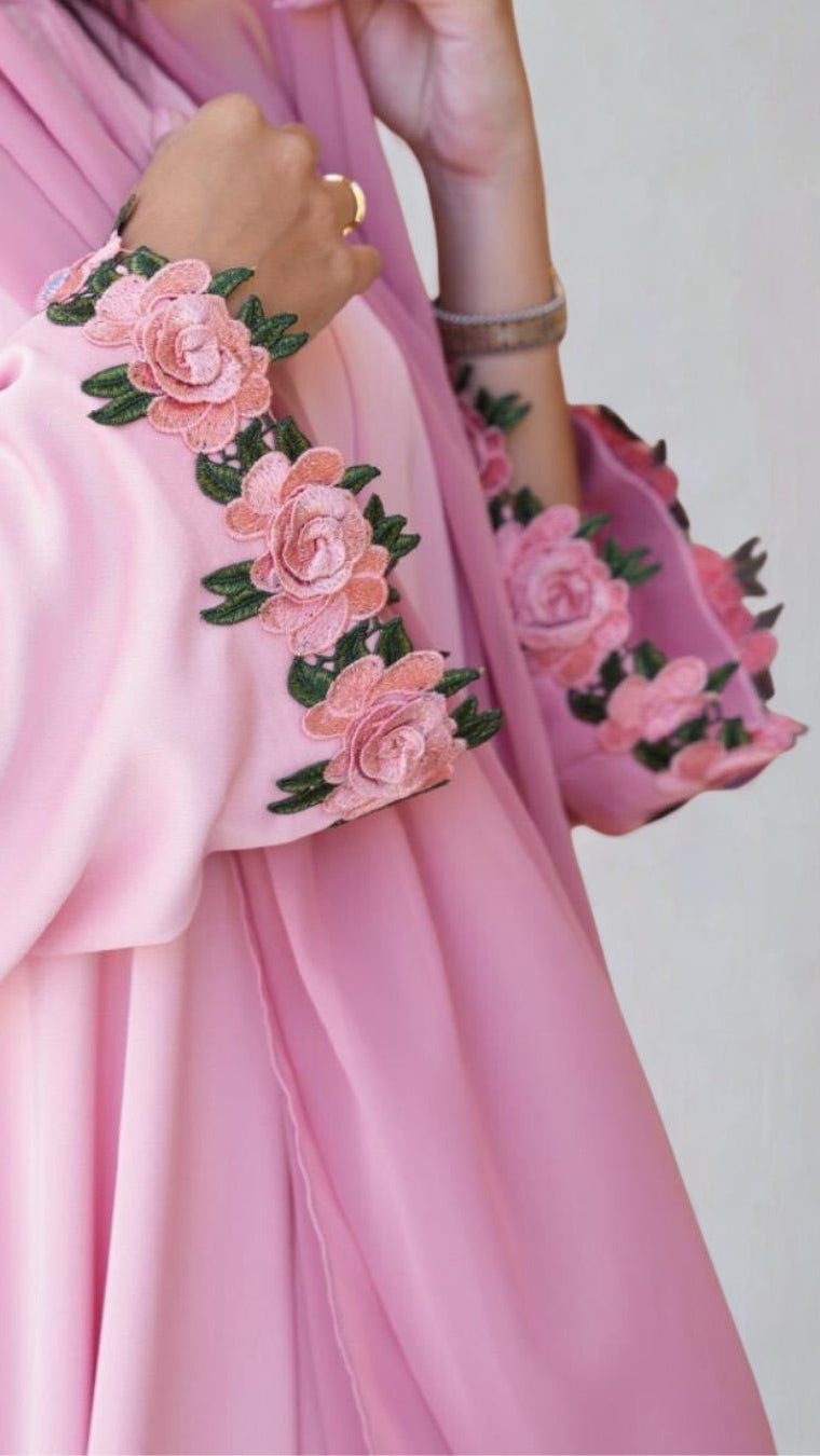 Pink outfit with floral embroidery on a plain background