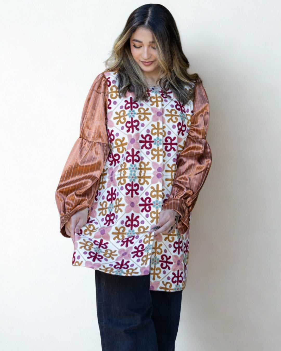 Woman wearing a patterned top with a plain background