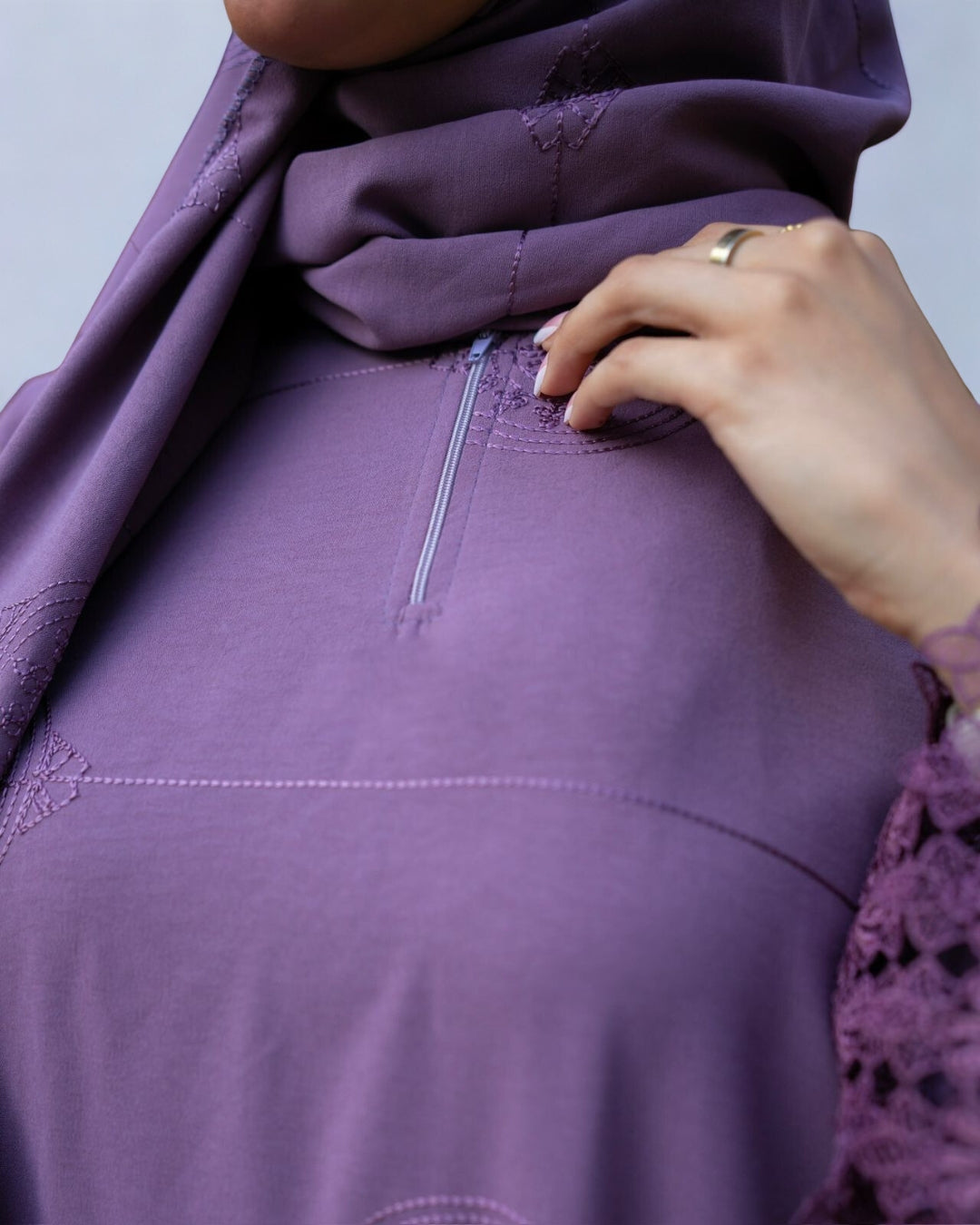 Close-up of a person wearing a purple outfit with a zipper detail.