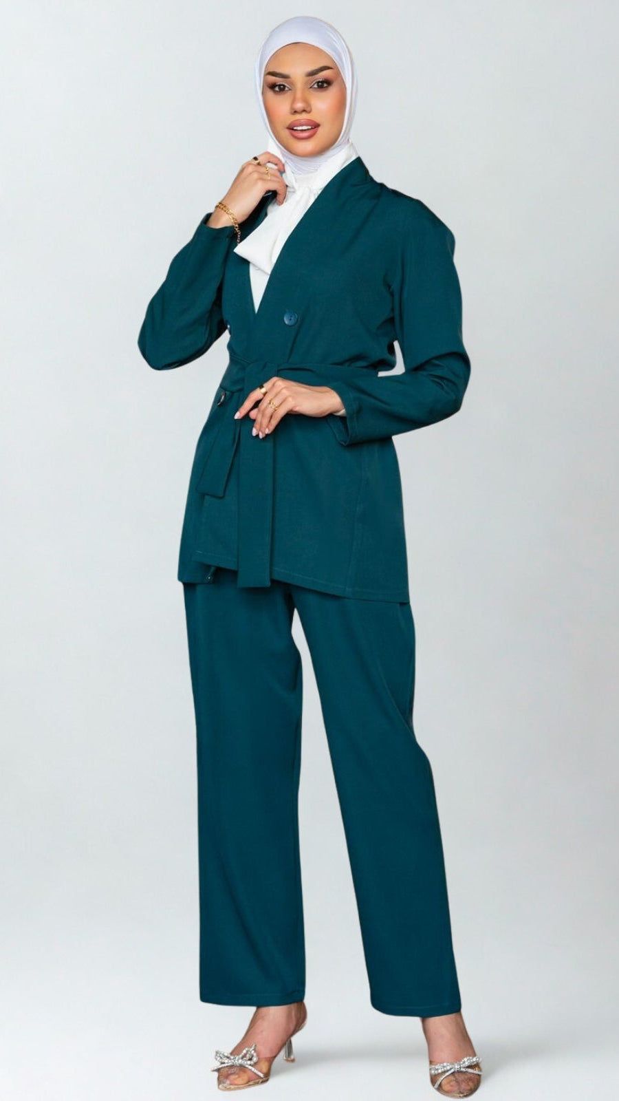 Woman wearing a teal suit with a white hijab on a white background