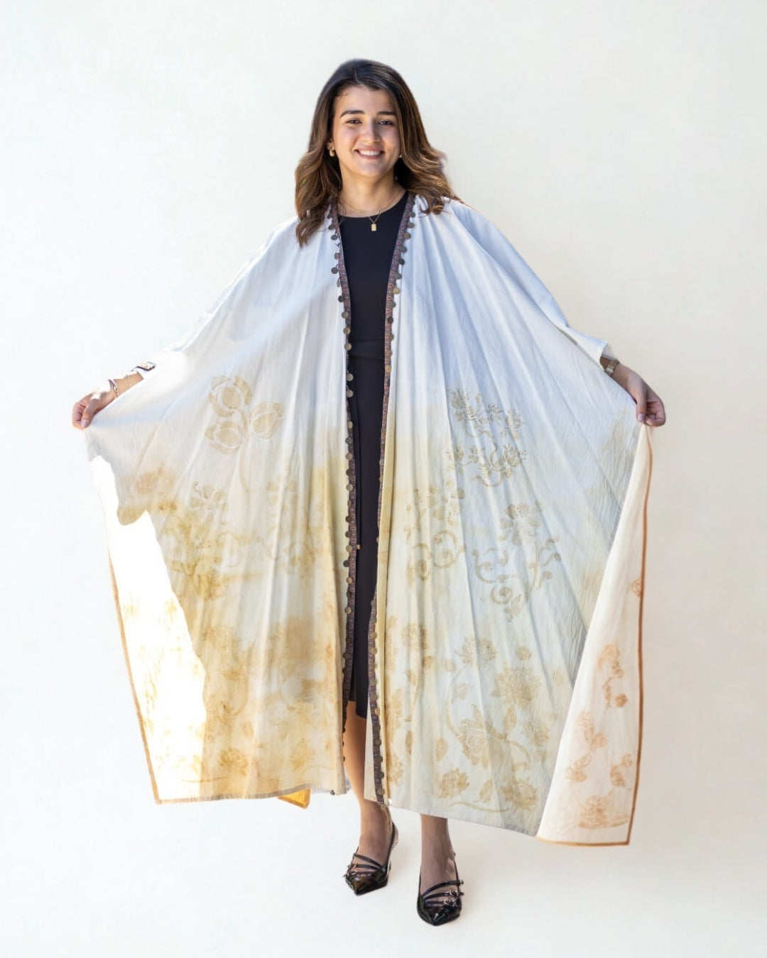 Woman holding a long, light-colored scarf with floral patterns on a white background