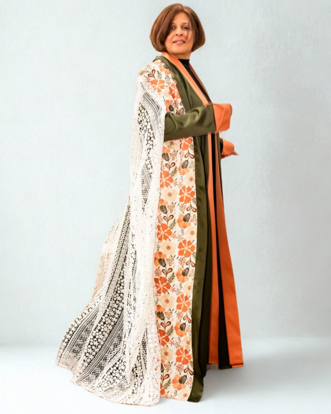 Woman wearing a long, patterned dress with floral design on a plain background