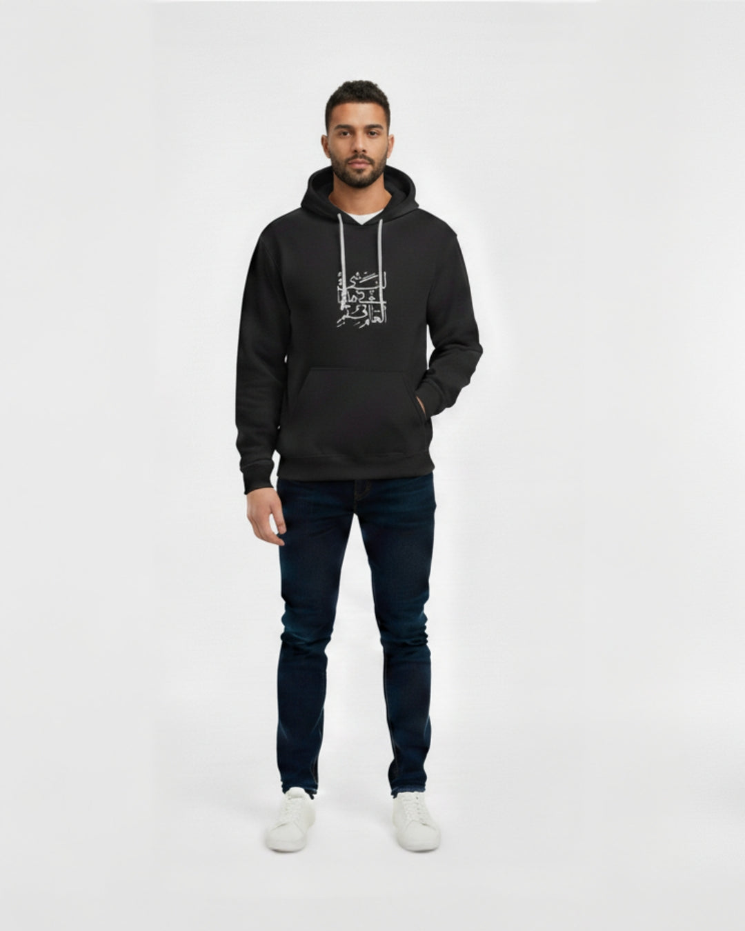 Man wearing a black hoodie with text and dark jeans on a white background
