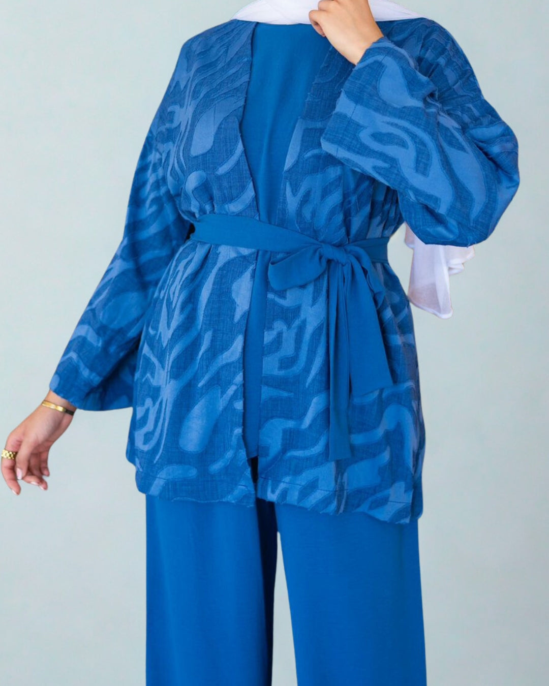 Blue patterned outfit with a belt on a plain background