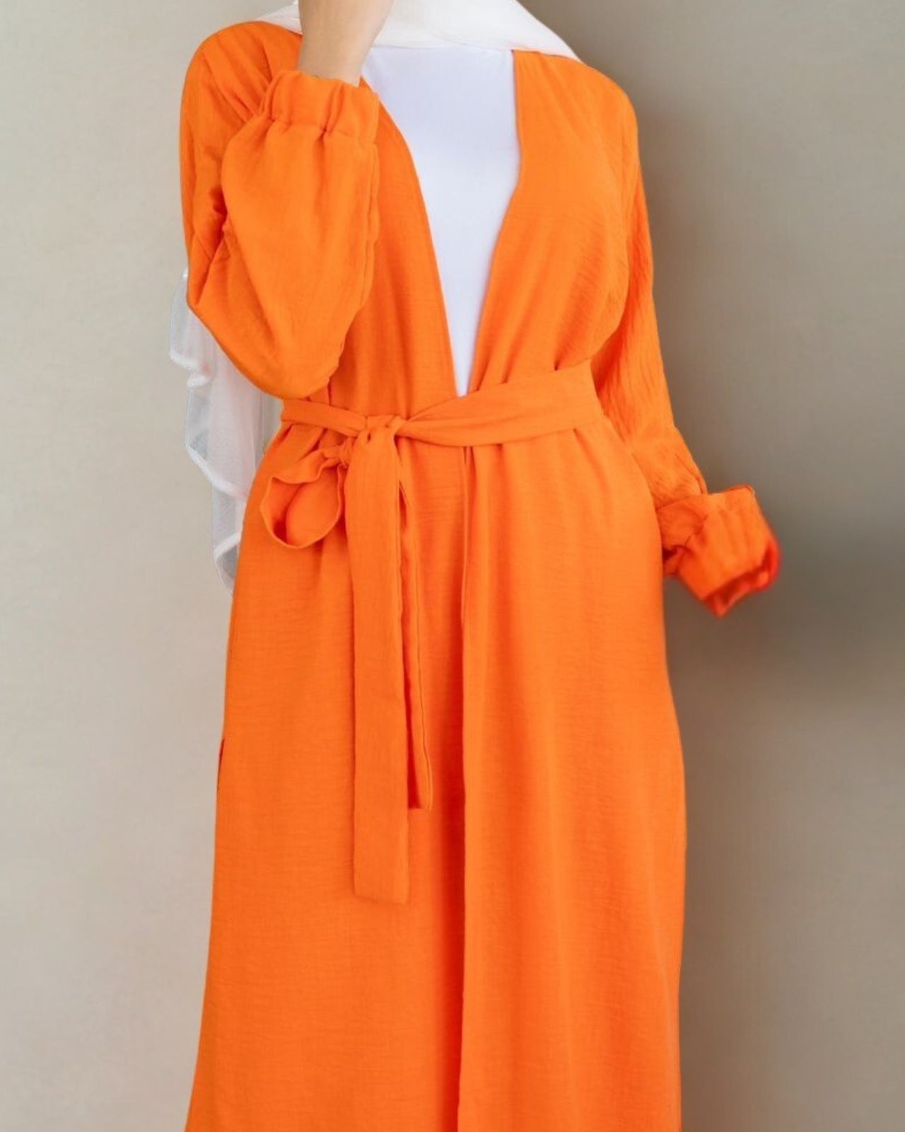 Orange dress with a belt on a mannequin against a beige background