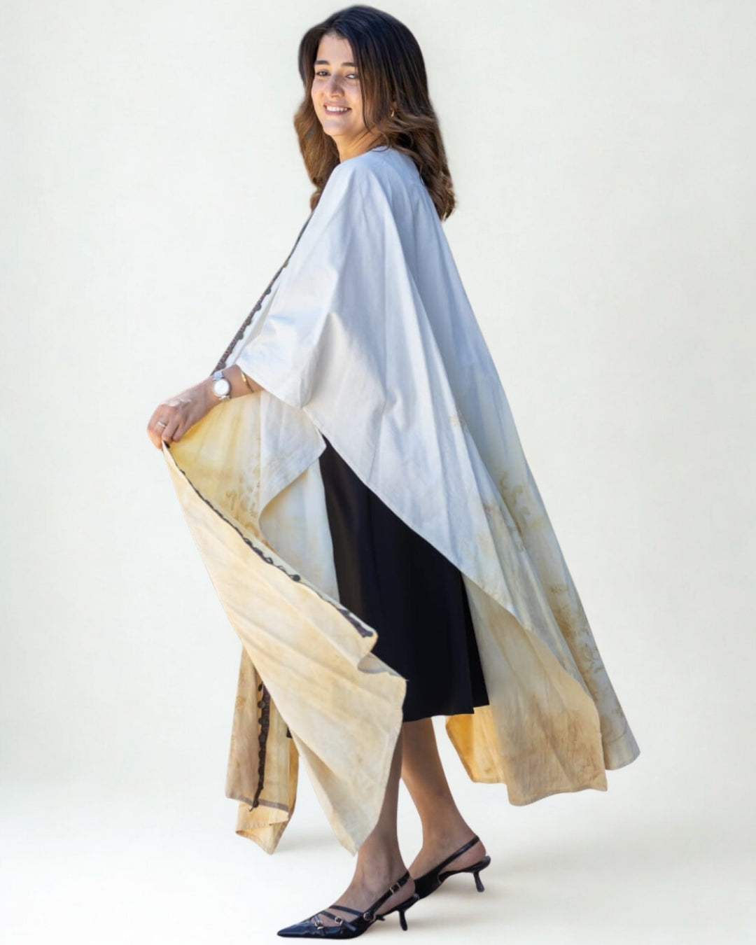 Woman holding a long, light-colored scarf against a white background