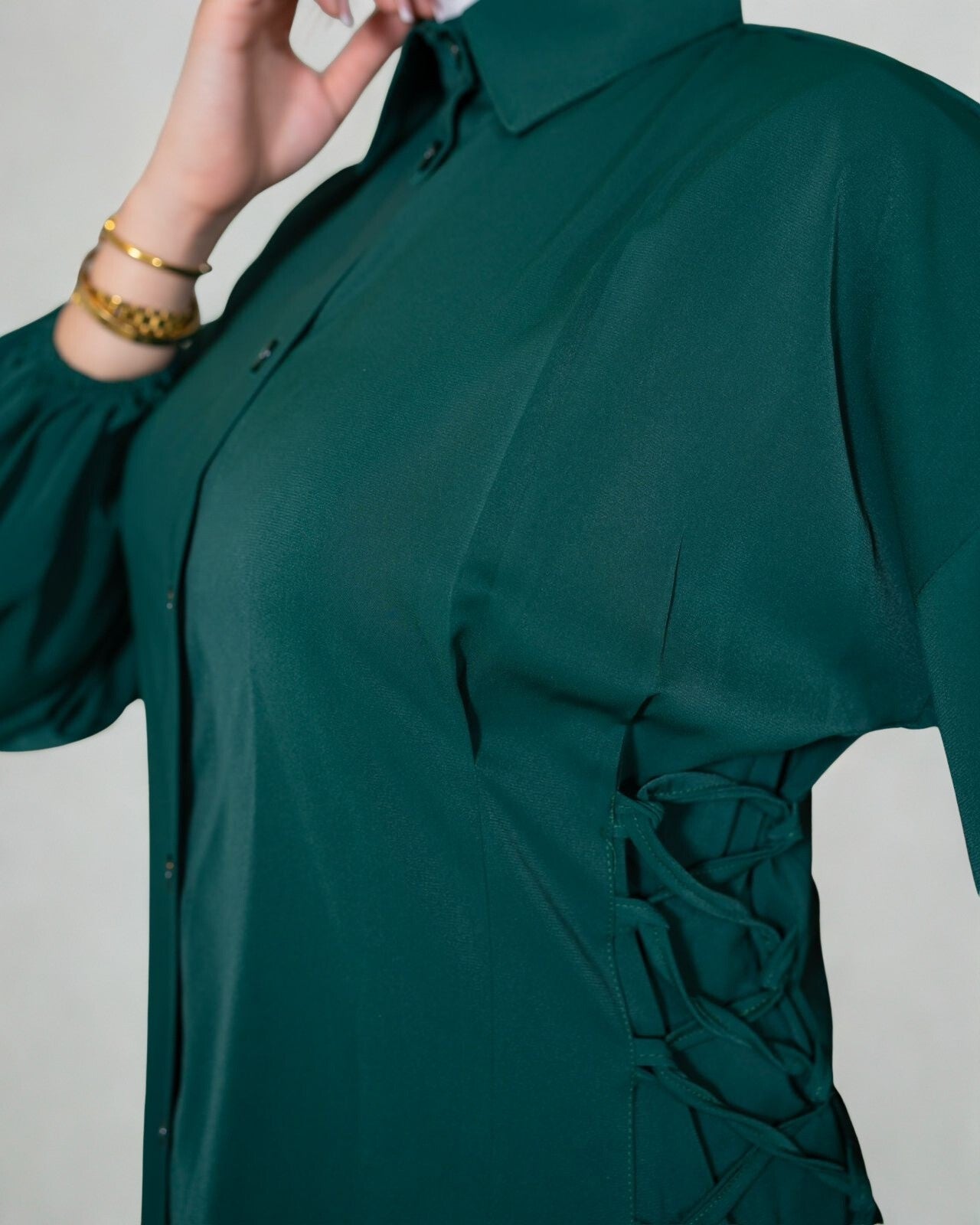 Green shirt with lace-up front detail on a plain background