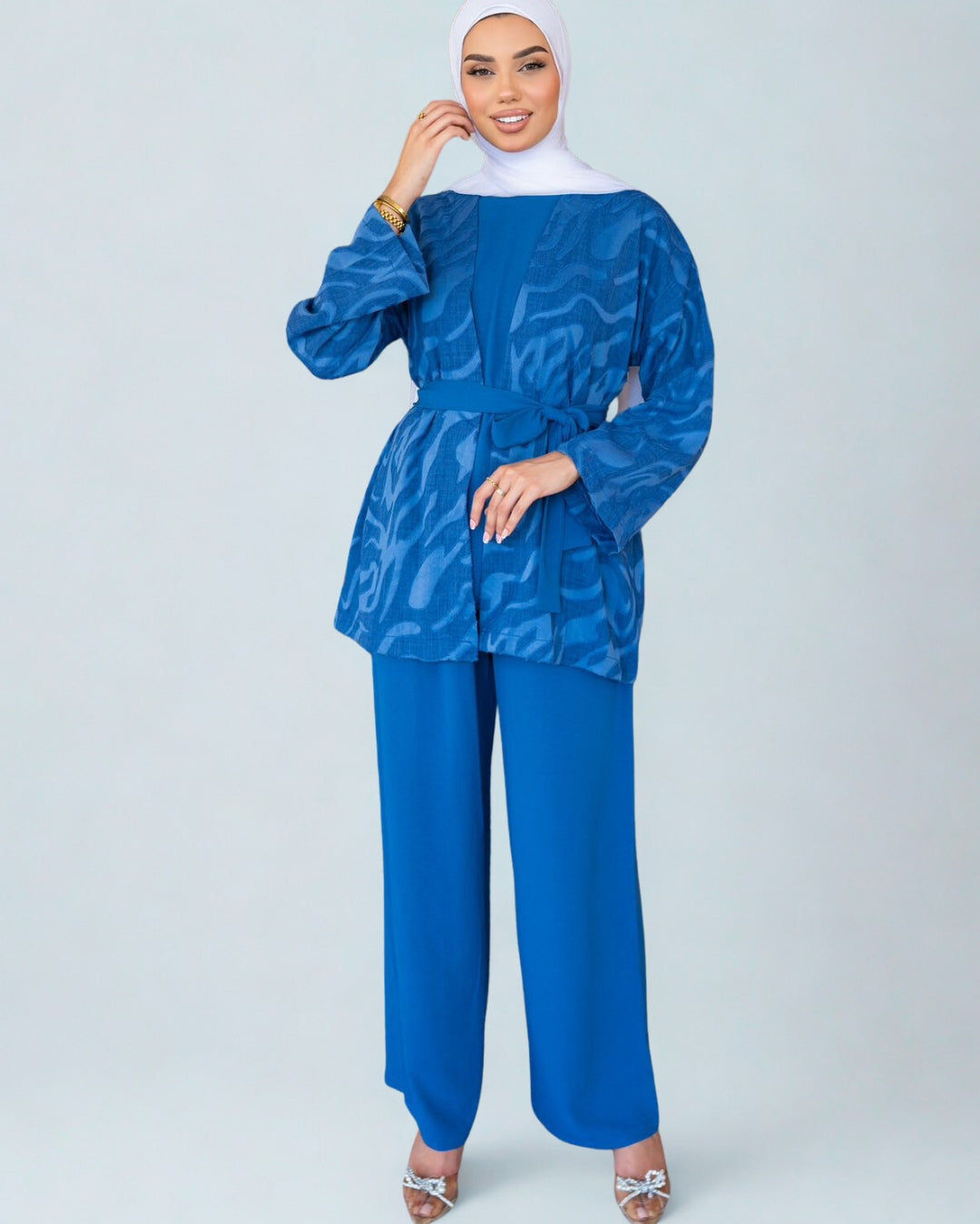 Woman wearing a blue patterned top and matching pants on a white background