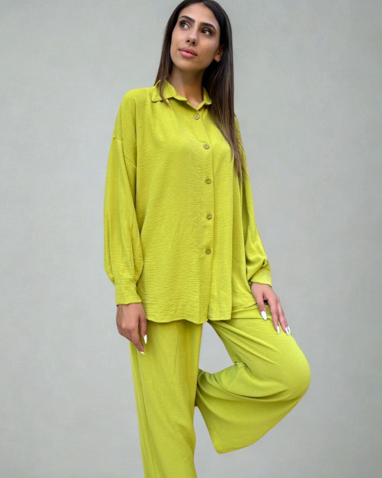Woman wearing a bright green outfit against a plain background