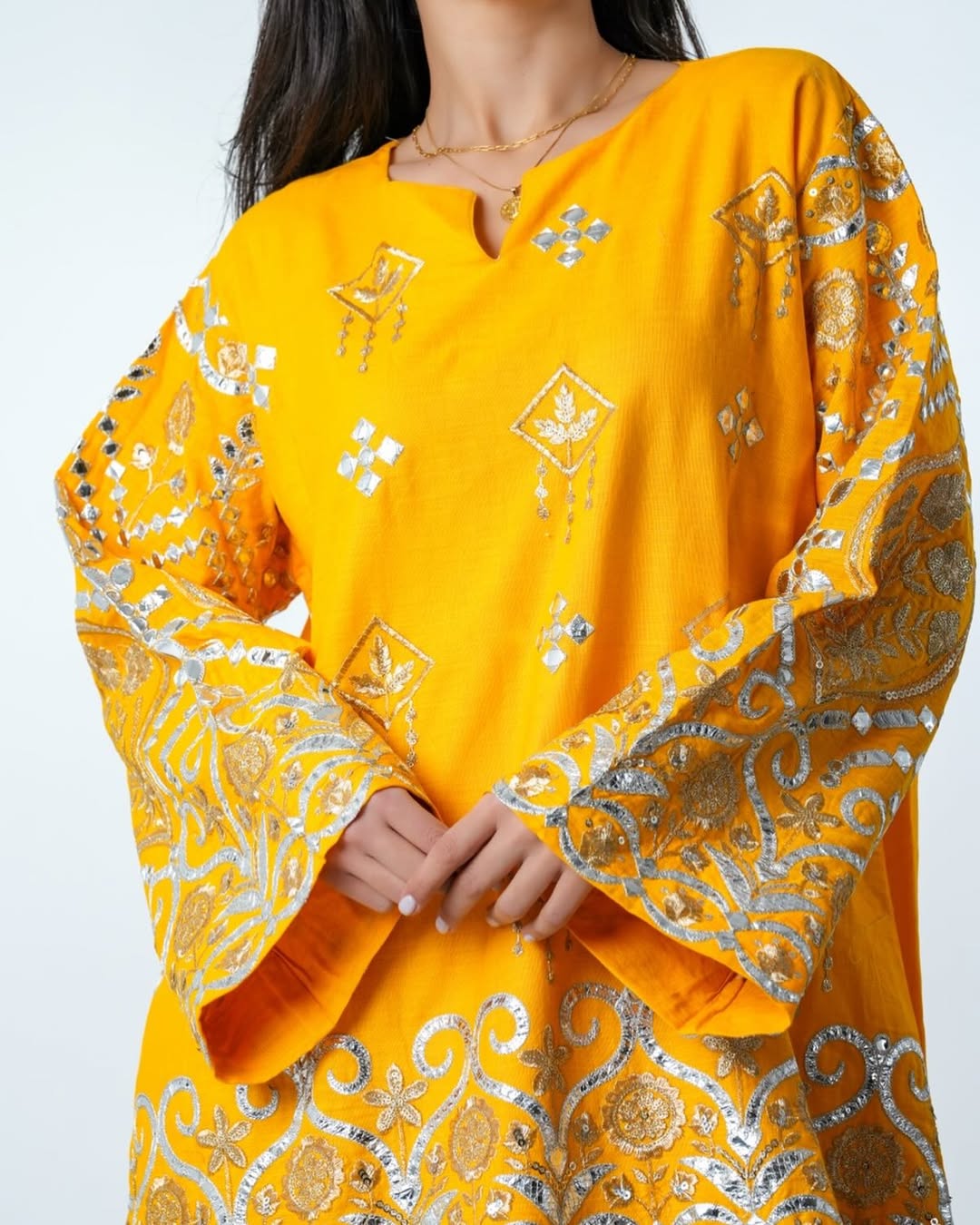 Yellow embroidered traditional outfit with intricate patterns on a white background
