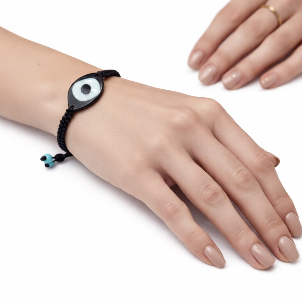 Hand wearing a black bracelet with a white eye design on a white background