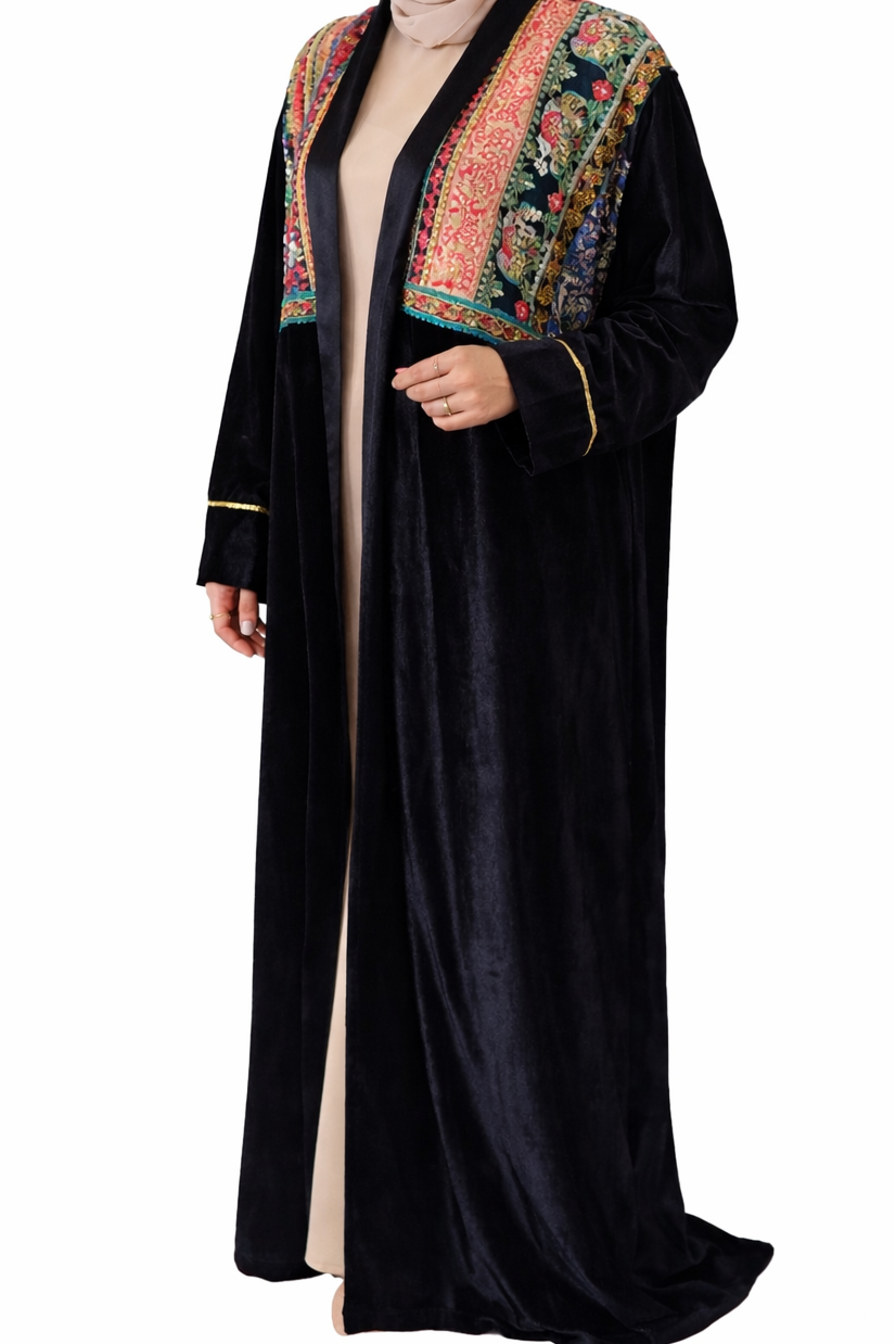Woman wearing a black abaya with colorful embroidery on a white background